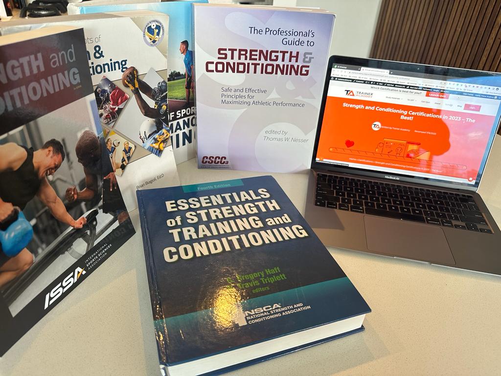 All of the best strength and conditioning certs with covers showing and laptop open